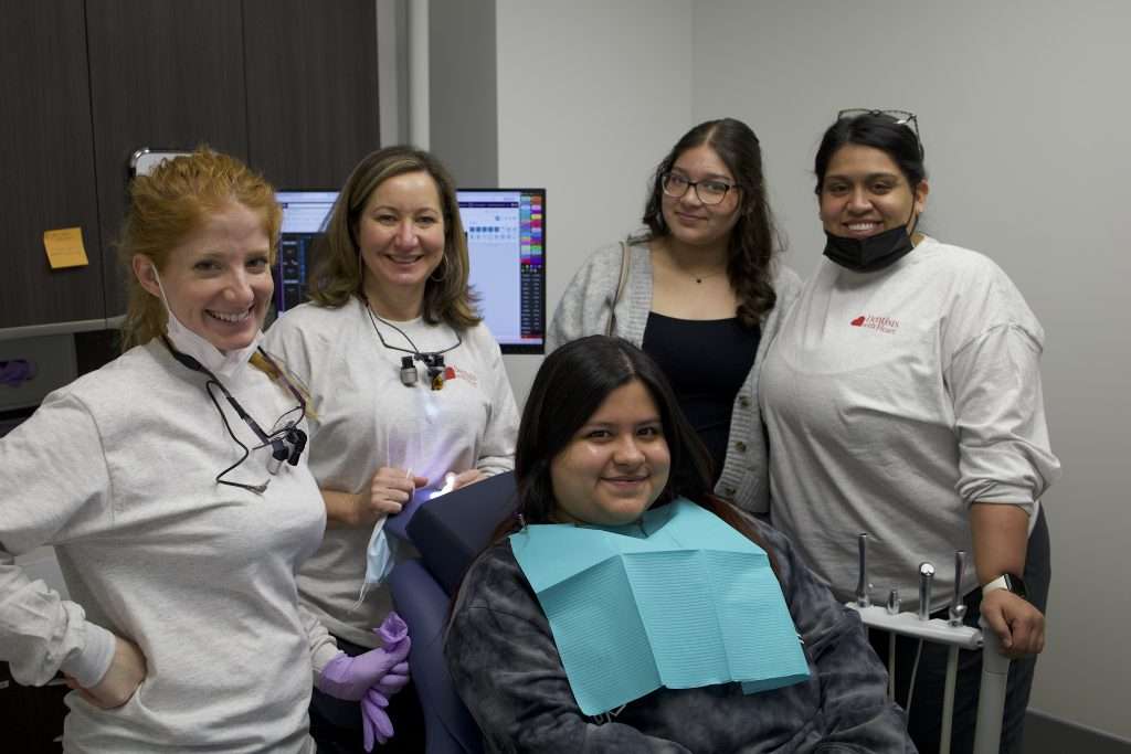 Dental team with a patient, all smiling and wearing masks